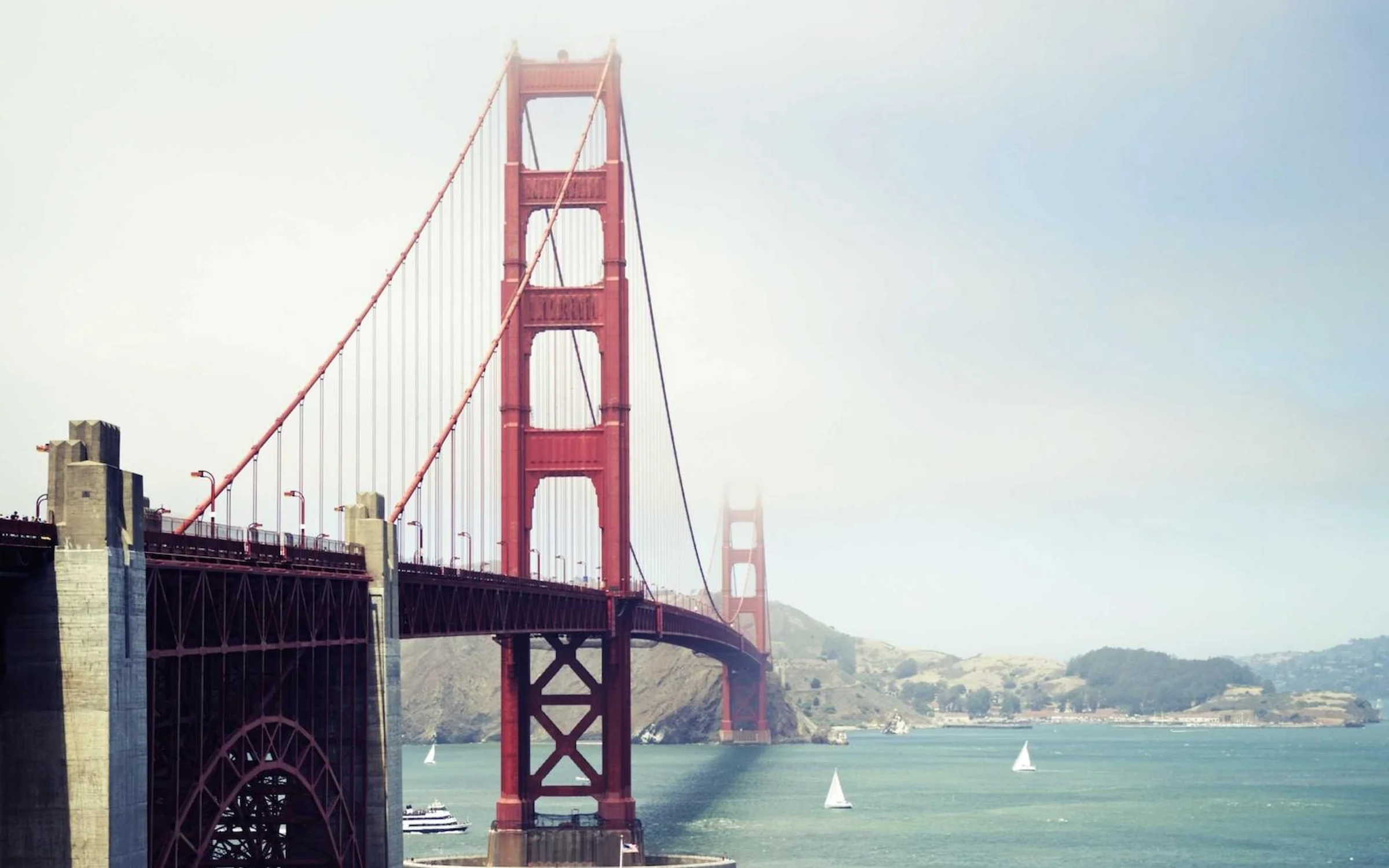 Pilier rouge du Golden Gate Bridge au-dessus de la baie de San Francisco, voiliers sur l'eau