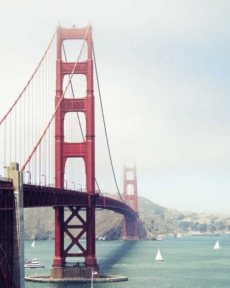 Pilier rouge du Golden Gate Bridge au-dessus de la baie de San Francisco, voiliers sur l'eau