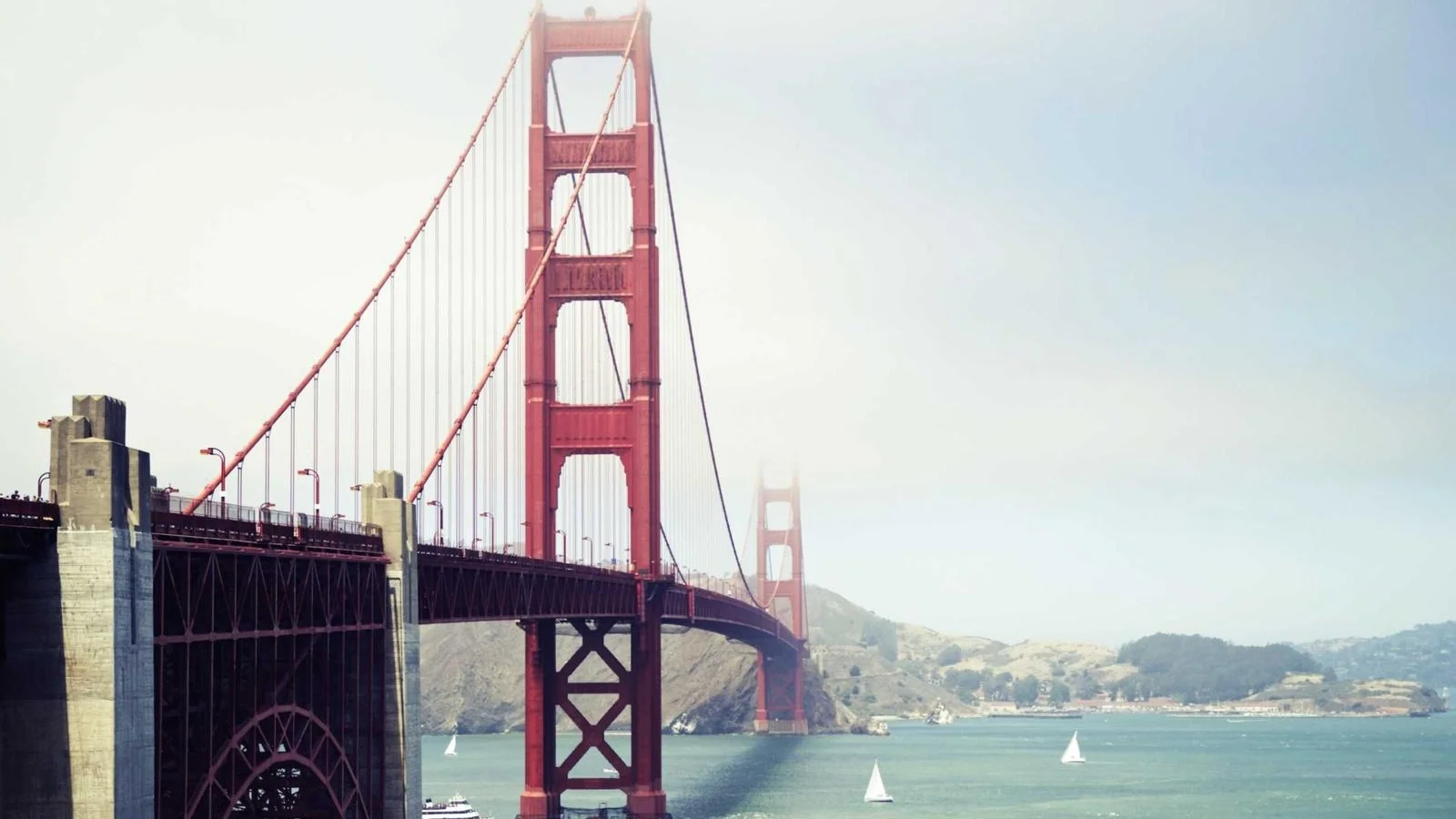 Pilier rouge du Golden Gate Bridge au-dessus de la baie de San Francisco, voiliers sur l'eau